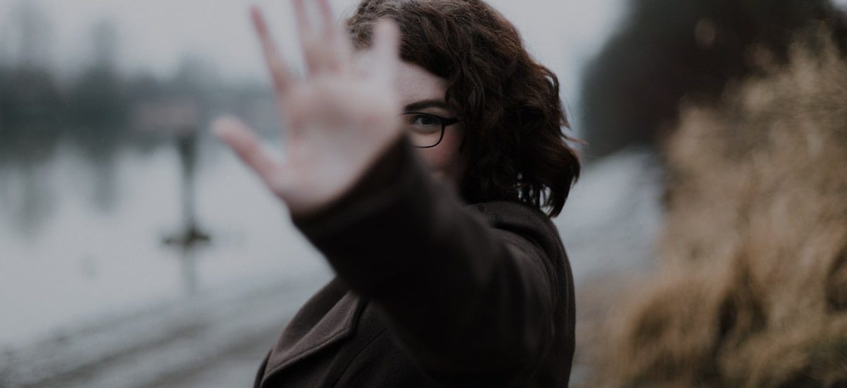 woman in black coat standing near body of water during daytime