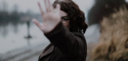 woman in black coat standing near body of water during daytime