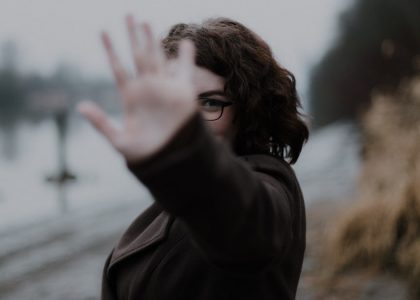 woman in black coat standing near body of water during daytime